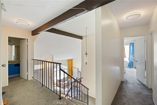 hallway featuring lofted ceiling with beams, carpet floors, and a textured ceiling