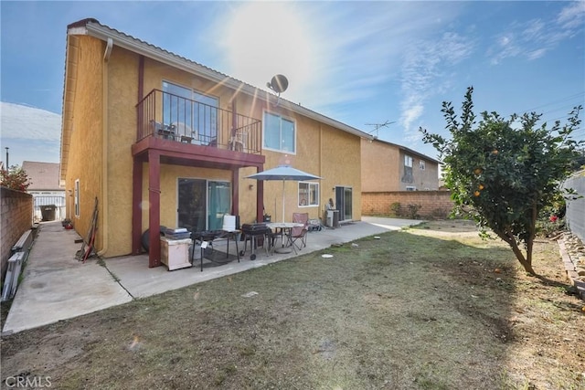 rear view of house featuring a patio, a balcony, and a lawn