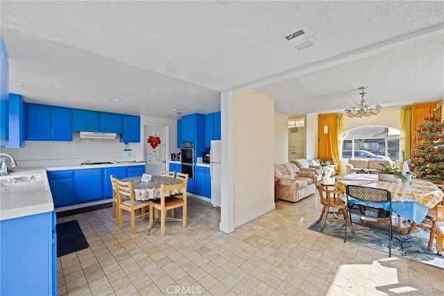 kitchen with sink, white refrigerator, a notable chandelier, gas stovetop, and blue cabinetry