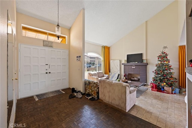 entrance foyer with a fireplace, high vaulted ceiling, dark parquet floors, and a textured ceiling