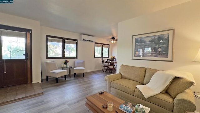 living room featuring ceiling fan, hardwood / wood-style floors, and a wall unit AC