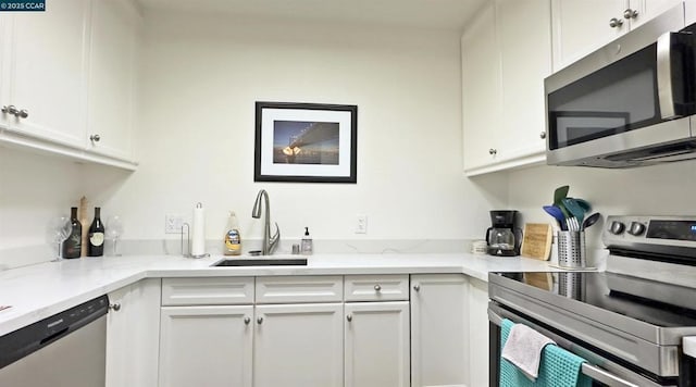 kitchen with stainless steel appliances, white cabinetry, and sink