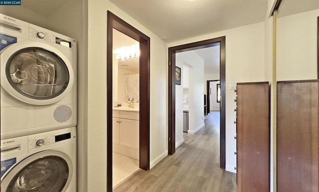 laundry area with stacked washer and dryer and light hardwood / wood-style floors