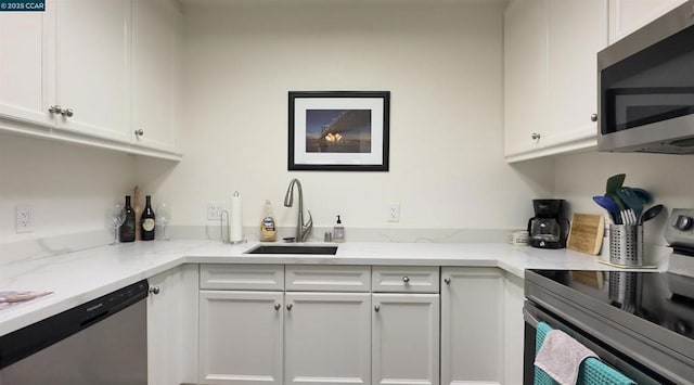 kitchen featuring stainless steel appliances, light stone countertops, sink, and white cabinets