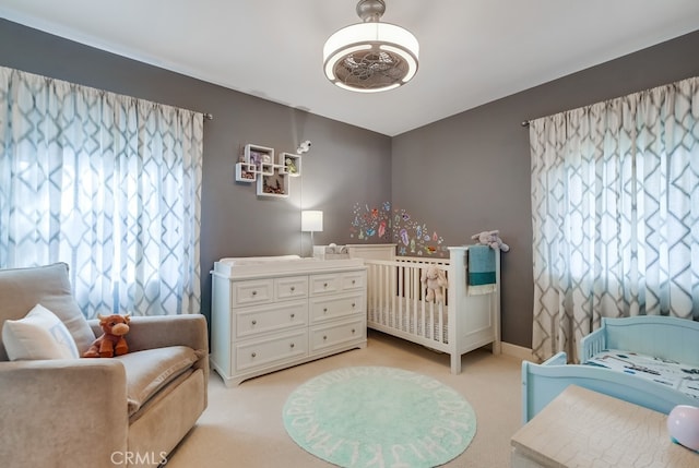 bedroom featuring a crib and light carpet