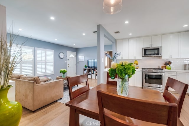 kitchen with backsplash, stainless steel appliances, light wood-type flooring, and white cabinets