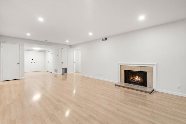 unfurnished living room with a high end fireplace and light hardwood / wood-style floors