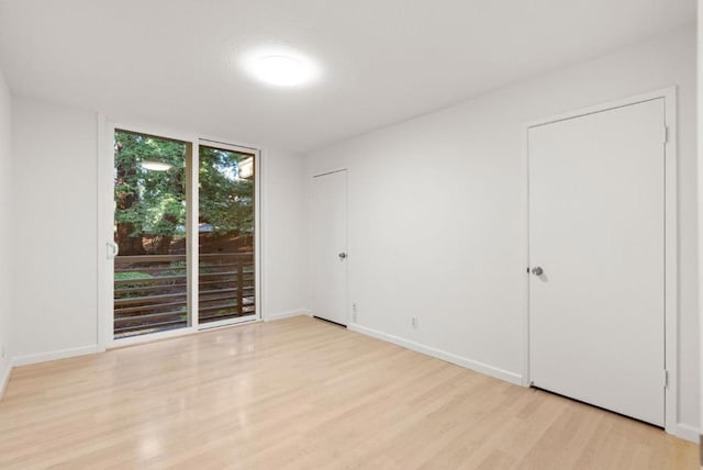 spare room featuring floor to ceiling windows and light hardwood / wood-style floors