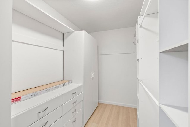 walk in closet with light hardwood / wood-style floors