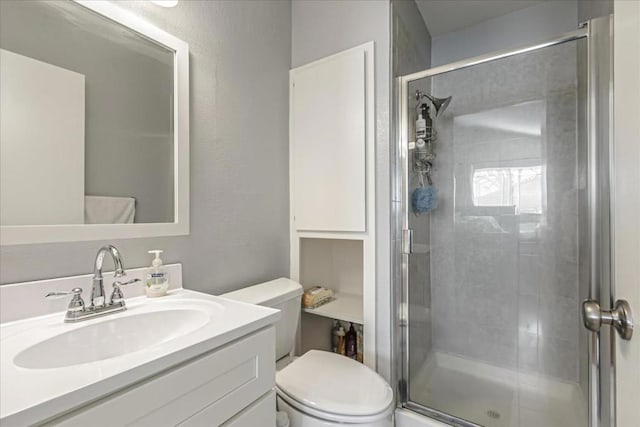 bathroom with a shower with door, vanity, and toilet