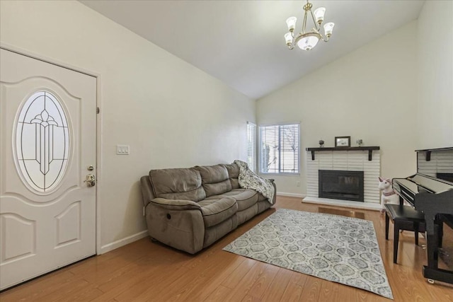 living room featuring a fireplace, a notable chandelier, light hardwood / wood-style flooring, and high vaulted ceiling