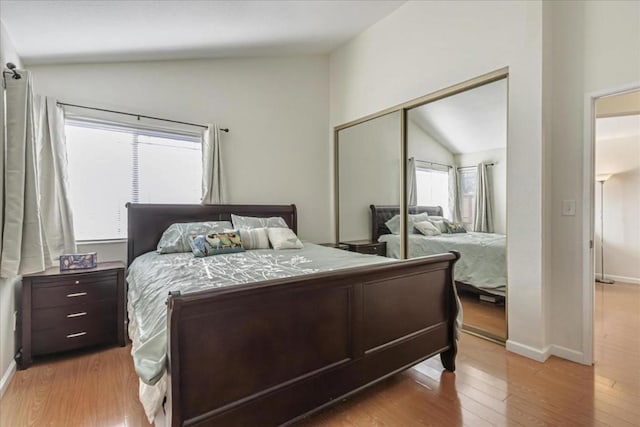 bedroom featuring lofted ceiling, light hardwood / wood-style floors, and a closet