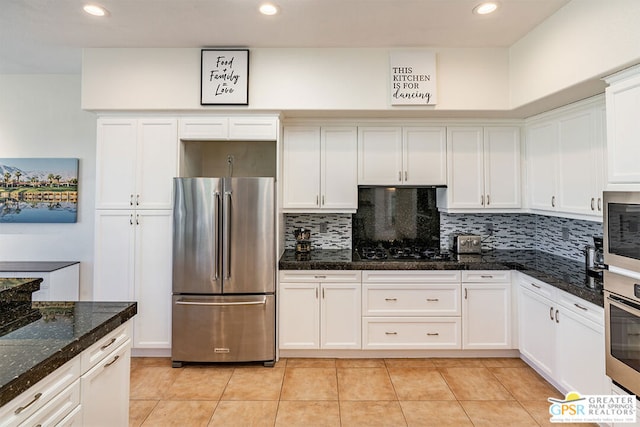 kitchen with white cabinetry, appliances with stainless steel finishes, dark stone countertops, and backsplash