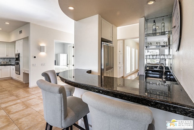 kitchen with white cabinetry, fridge, a breakfast bar, and kitchen peninsula