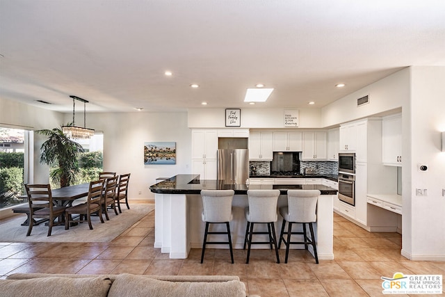 kitchen with a kitchen island, a breakfast bar, white cabinetry, hanging light fixtures, and stainless steel appliances