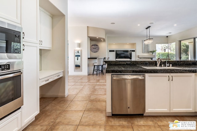 kitchen with sink, decorative light fixtures, light tile patterned floors, stainless steel appliances, and white cabinets