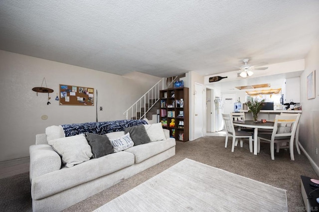 carpeted living room featuring ceiling fan and a textured ceiling