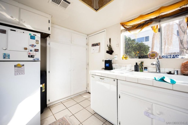 kitchen featuring light tile patterned flooring, sink, white cabinetry, tile countertops, and white appliances