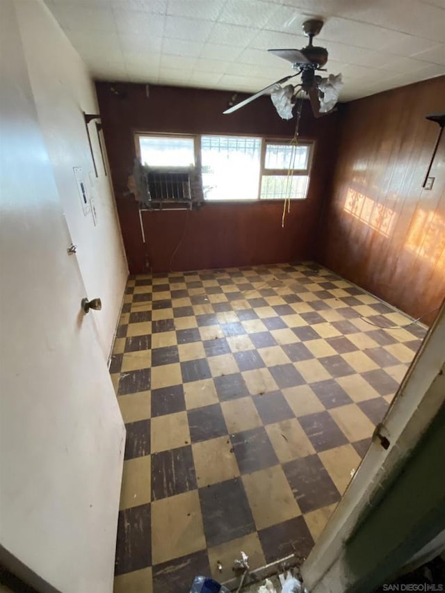 empty room featuring cooling unit, ceiling fan, and wood walls