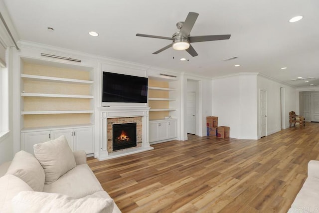 living room featuring crown molding, built in features, ceiling fan, and light hardwood / wood-style flooring