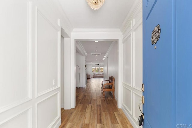 corridor with light hardwood / wood-style flooring and ornamental molding