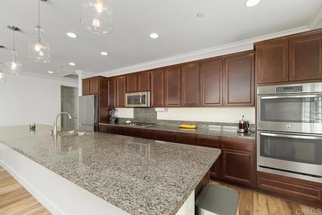 kitchen featuring appliances with stainless steel finishes, decorative light fixtures, sink, ornamental molding, and light stone countertops