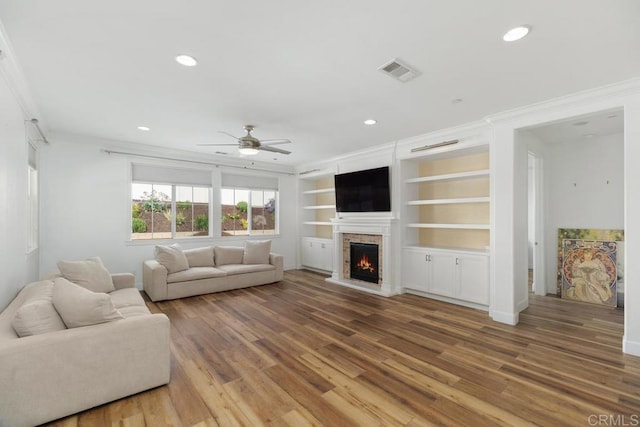 living room with crown molding, hardwood / wood-style floors, and built in shelves