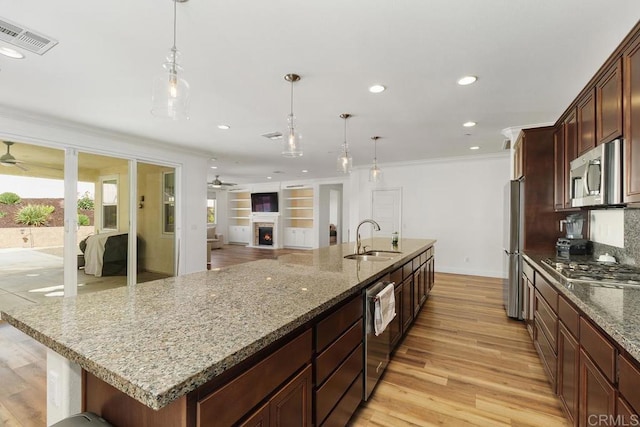 kitchen featuring stainless steel appliances, hanging light fixtures, sink, and a large island with sink