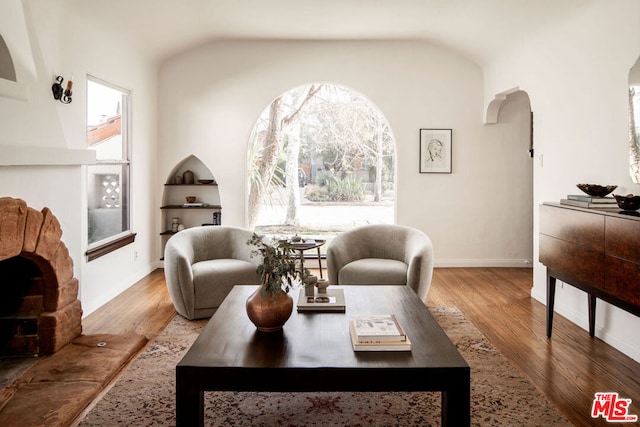 living room with lofted ceiling, built in shelves, and light wood-type flooring