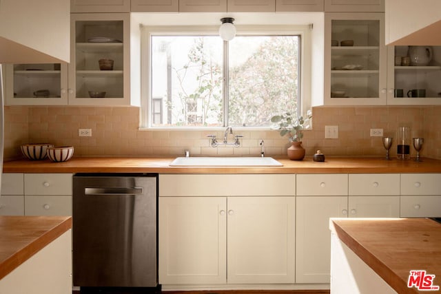 kitchen featuring sink, wooden counters, dishwasher, white cabinets, and decorative backsplash