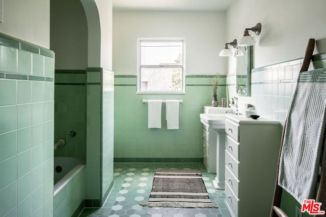 bathroom with vanity, bathing tub / shower combination, tile patterned flooring, and tile walls