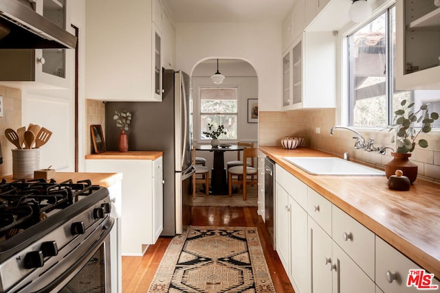 kitchen with butcher block counters, sink, light hardwood / wood-style flooring, appliances with stainless steel finishes, and white cabinets