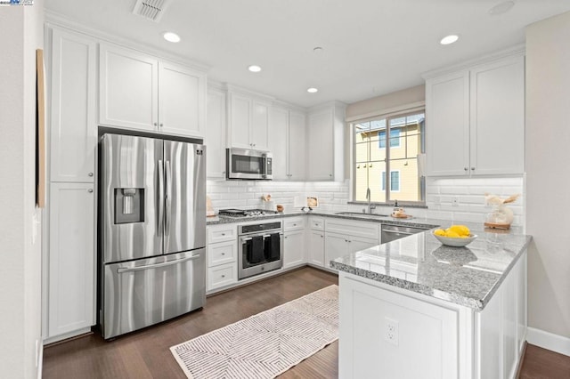 kitchen with appliances with stainless steel finishes, white cabinetry, sink, light stone countertops, and dark wood-type flooring