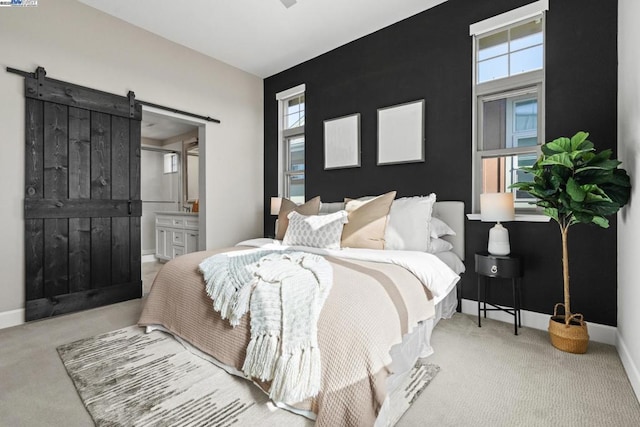 carpeted bedroom with a barn door and ensuite bath