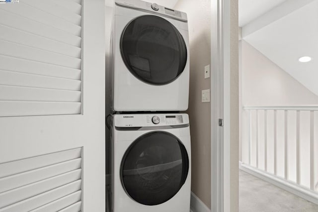 laundry area with stacked washer / dryer and light carpet