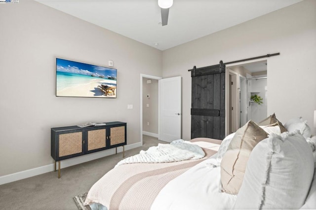 bedroom with a spacious closet, light colored carpet, a barn door, and ceiling fan