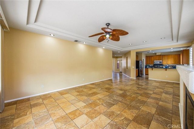 unfurnished living room with ceiling fan and a raised ceiling