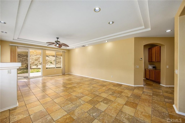 unfurnished living room featuring a raised ceiling and ceiling fan