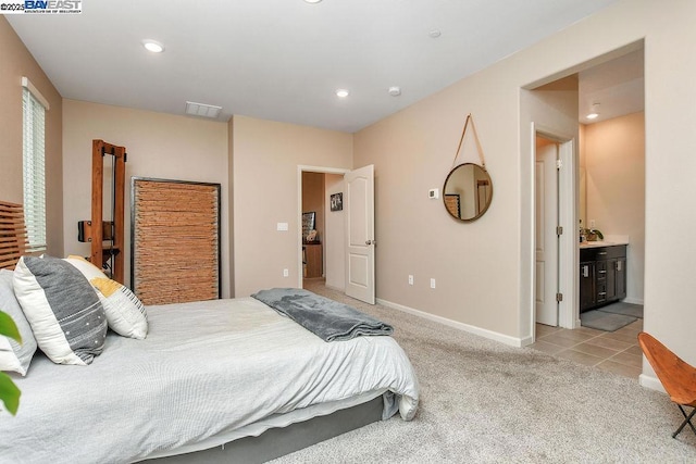 carpeted bedroom with ensuite bathroom and sink