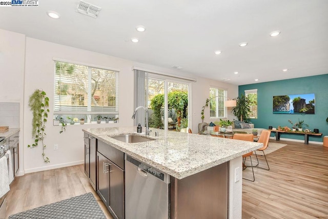 kitchen featuring dark brown cabinets, sink, stainless steel dishwasher, and light wood-type flooring