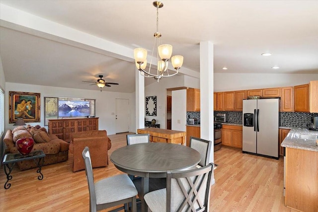 dining area with lofted ceiling, ceiling fan with notable chandelier, and light hardwood / wood-style floors