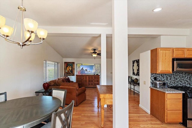 dining area featuring vaulted ceiling, ceiling fan with notable chandelier, and light hardwood / wood-style floors