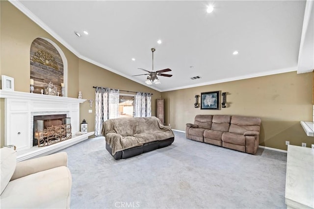 carpeted living room featuring a premium fireplace, crown molding, lofted ceiling, and ceiling fan