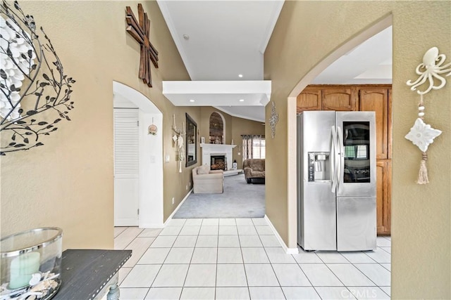 kitchen featuring vaulted ceiling, light tile patterned floors, and stainless steel fridge with ice dispenser