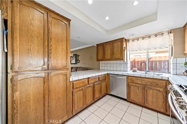 kitchen featuring appliances with stainless steel finishes, backsplash, tile counters, light tile patterned floors, and a raised ceiling