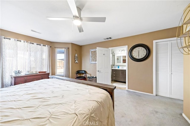 bedroom with ceiling fan, light carpet, and ensuite bath