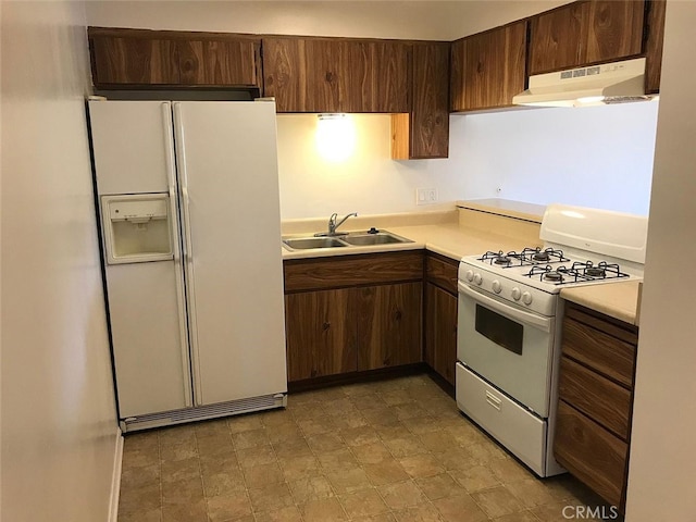 kitchen with white appliances, dark brown cabinetry, and sink