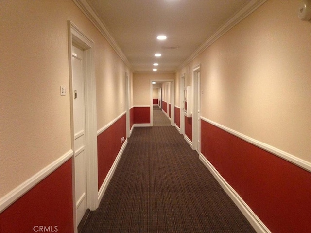 corridor featuring dark colored carpet and ornamental molding