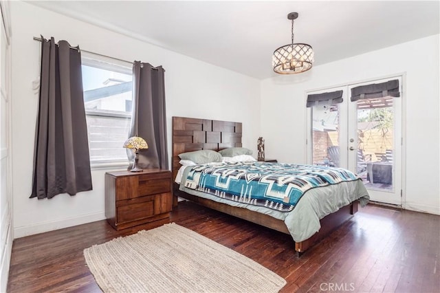 bedroom with multiple windows, dark hardwood / wood-style floors, and access to outside