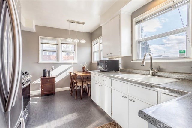 kitchen with stainless steel appliances, decorative light fixtures, sink, and white cabinets